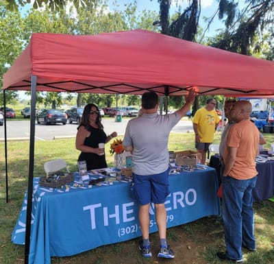 Staff interacting with visitors at an informational booth outdoors