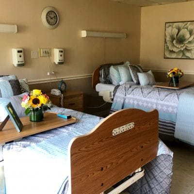 A shared resident room with two beds and flowers