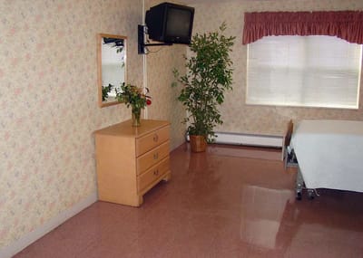 Simple resident room with a bed and dresser.