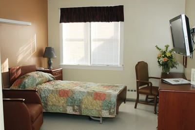 Interior view of a resident's room with bed and desk.