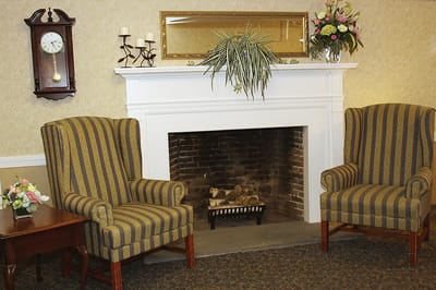 Cozy lounge area with two chairs and a fireplace.