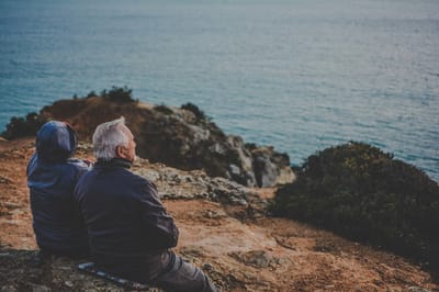 Two seniors enjoying a scenic view by the water.