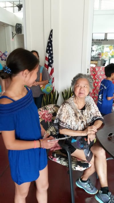 A senior resident and a young girl smiling indoors.