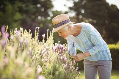 Senior woman enjoying flowers in a garden
