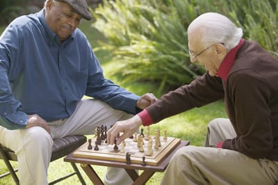 Two seniors engaged in a chess game outdoors.