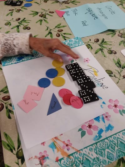 Hands playing a game with colorful tokens and paper.