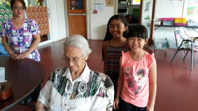 Elderly woman with two young girls in a social area.
