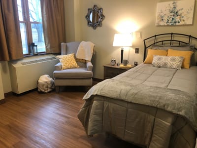 Cozy resident room with a bed and armchair.