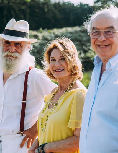 Three residents smiling outdoors in a garden setting