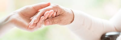 Close-up of a caregiver and resident holding hands