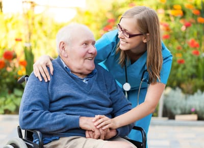 A caregiver with a resident in a colorful garden
