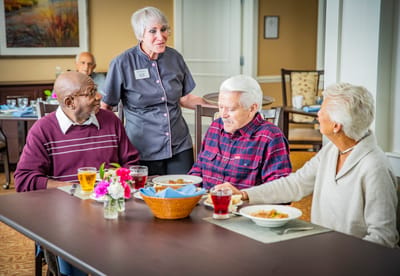 Residents enjoying a meal with staff in the dining room