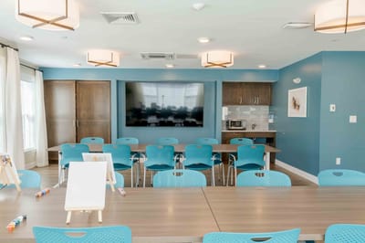Bright activity room with tables and blue chairs