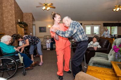 Residents and staff engaging in a dancing activity in a common area