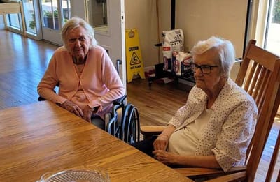 Two residents sitting at a table in a communal space