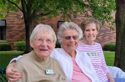 Three happy residents sitting outside in a garden