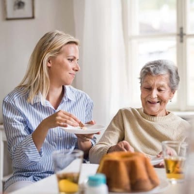 Caregiver enjoying cake with a resident in a cozy interior