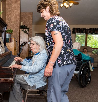 Residents engaging in a music activity with staff assistance