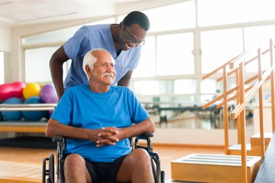 Caregiver assisting a resident in a rehabilitation gym