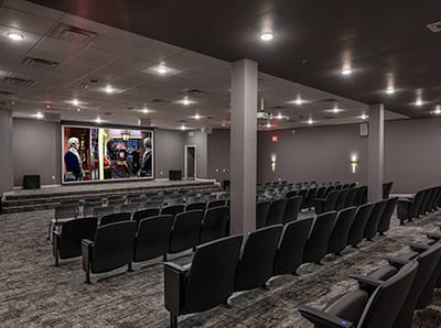 A modern theater room with seating and a large screen