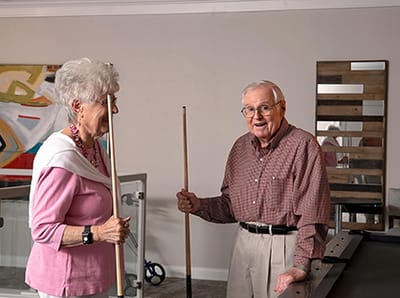 Two seniors playing pool in an activitiy room