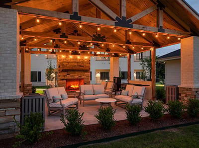 Cozy outdoor seating area with lights and fireplace