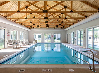 Indoor pool area with wooden ceiling and large windows