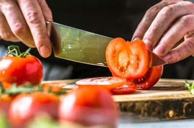 Close-up of hands slicing fresh tomatoes on a cutting board