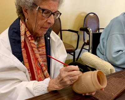 Resident painting a pottery piece in a common area