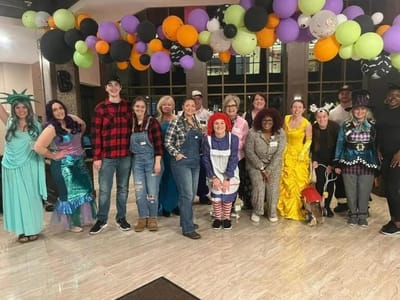 Staff and residents in costumes at a festive event