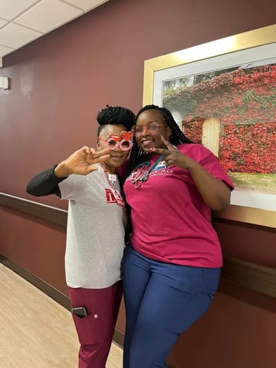 Two staff members posing playfully in a hallway