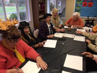 Residents engaging in an art activity wearing festive accessories