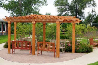An outdoor pergola with seating surrounded by greenery