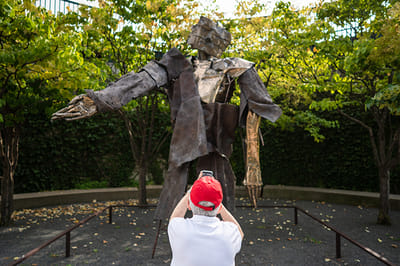 A resident photographing a sculpture in a garden