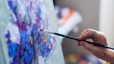 A resident painting on canvas in a bright art space