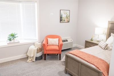 Cozy resident room with an orange armchair and bed