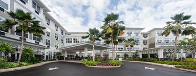 Front entrance of The Plaza Moanalualani with palm trees
