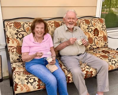 Two residents enjoying ice cream on a porch sofa