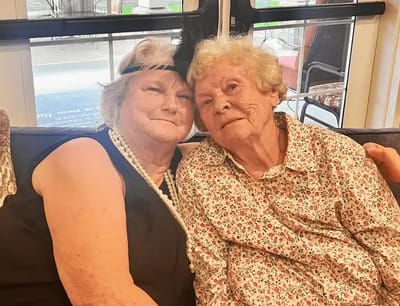 Two smiling residents sitting together on a couch