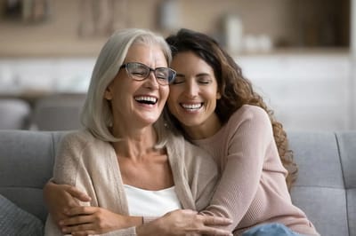Two women laughing and embracing on a couch.