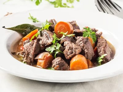 A dish of beef stew with carrots and herbs