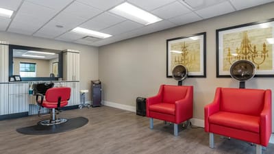 Hair salon area with red chairs and mirrors