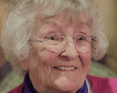 A smiling elderly woman with glasses