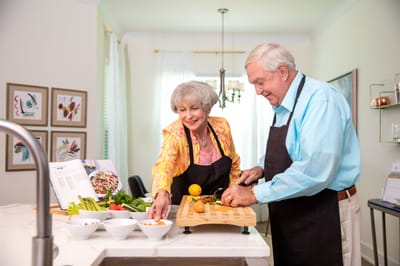 A senior couple cooking together in a bright kitchen