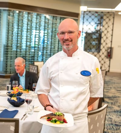 Chef presenting a gourmet meal in the dining area