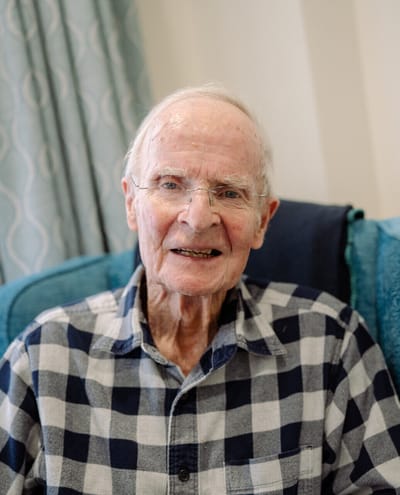 An elderly man smiling in a comfortable chair