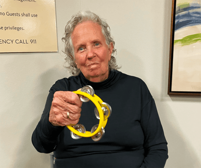 Resident enjoying a music activity with a tambourine