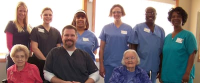 Staff and residents posing together in an activity room