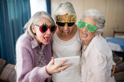 Three smiling elderly women wearing fun sunglasses