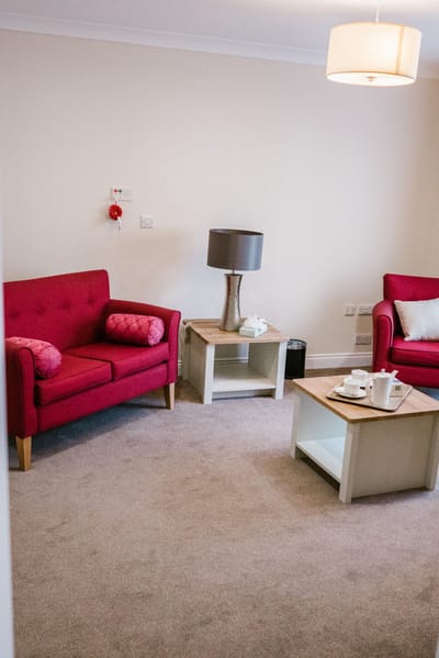 A cozy seating area with pink sofas and a lamp